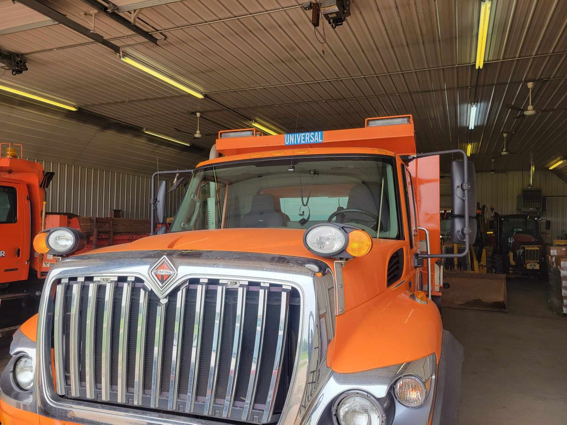 An orange dump truck is parked in a garage.