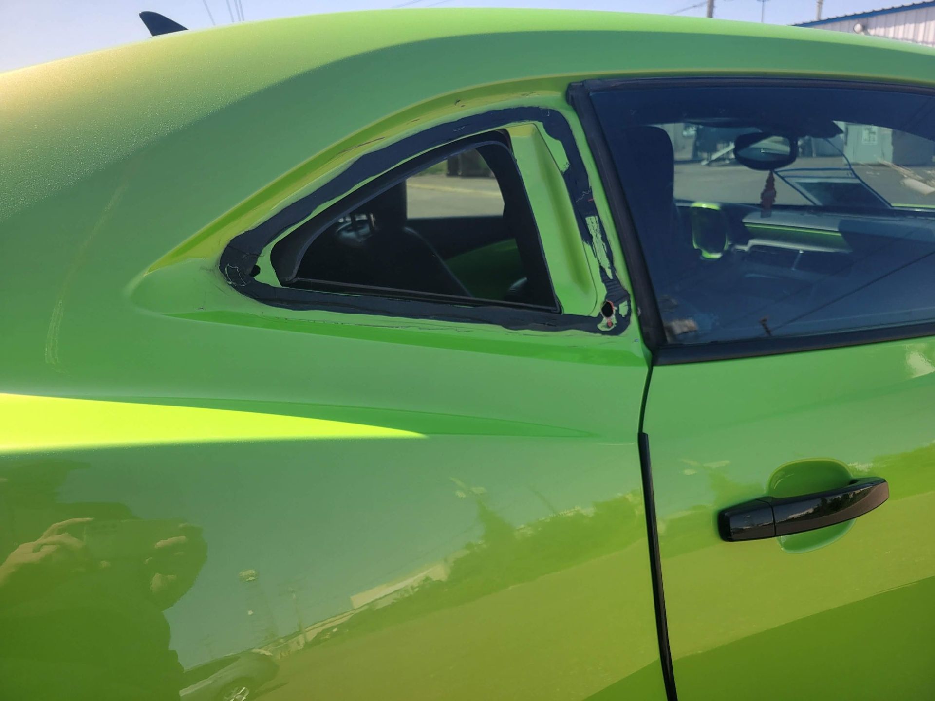 A green car is parked in front of a building