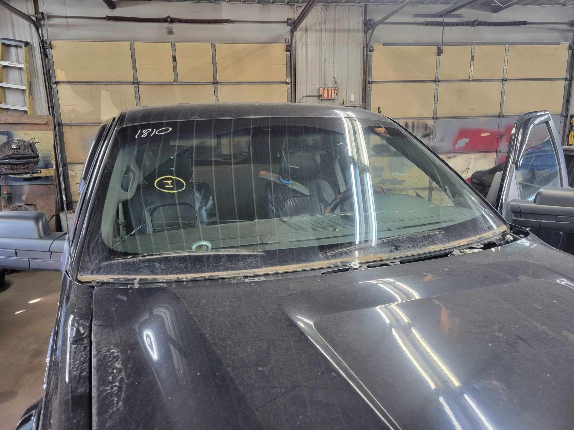 A black truck with a broken windshield is parked in a garage.