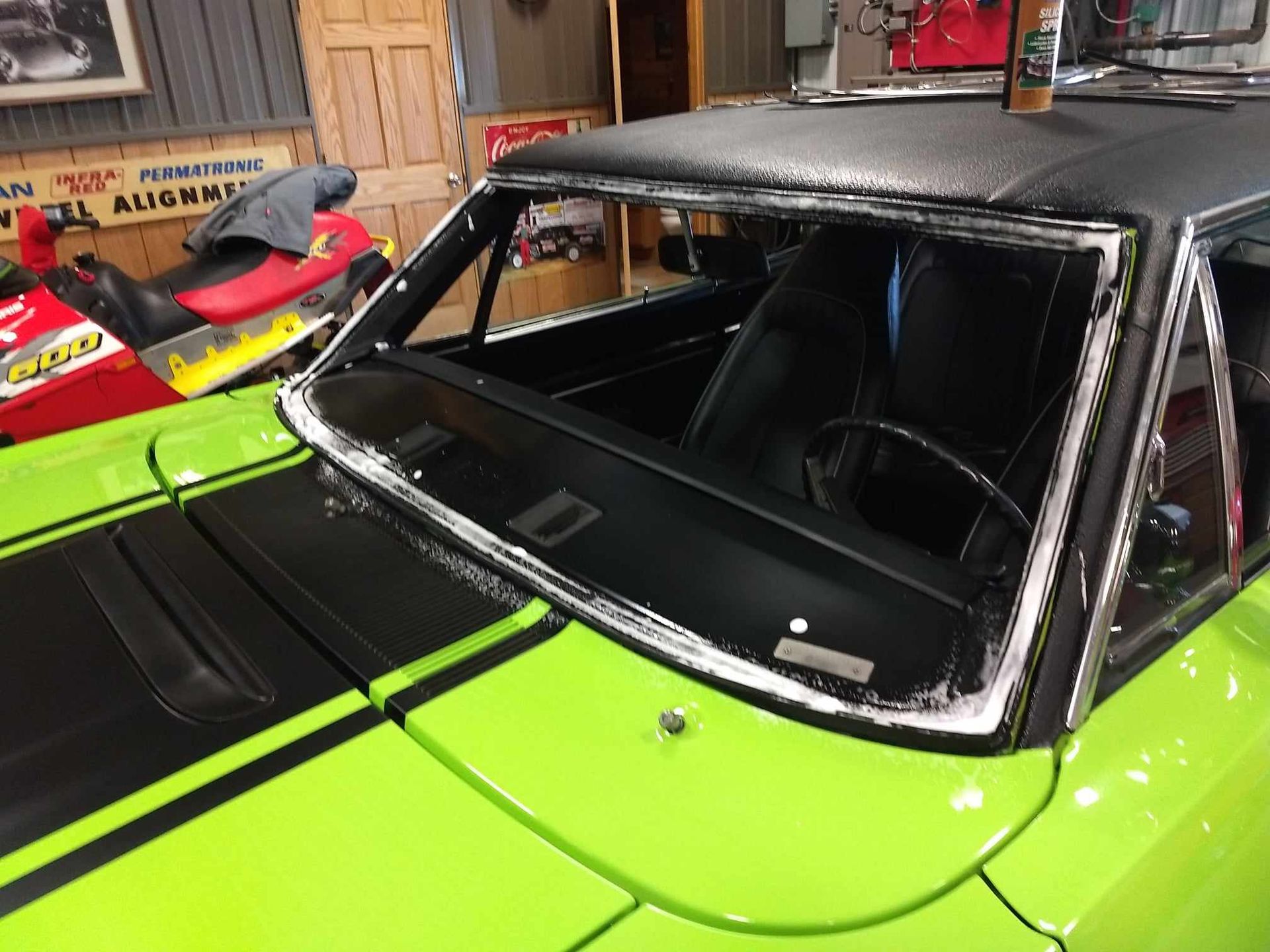 A green car with a black top is parked in a garage