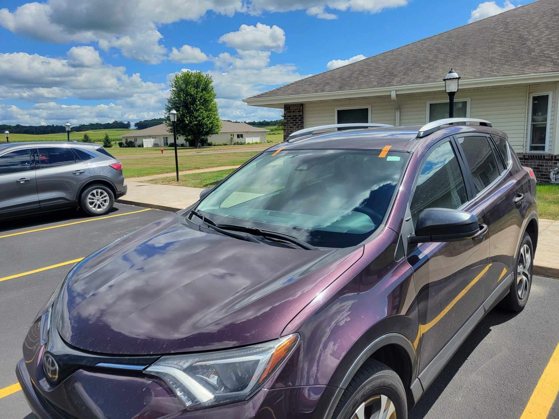 A purple car is parked in a parking lot in front of a building.