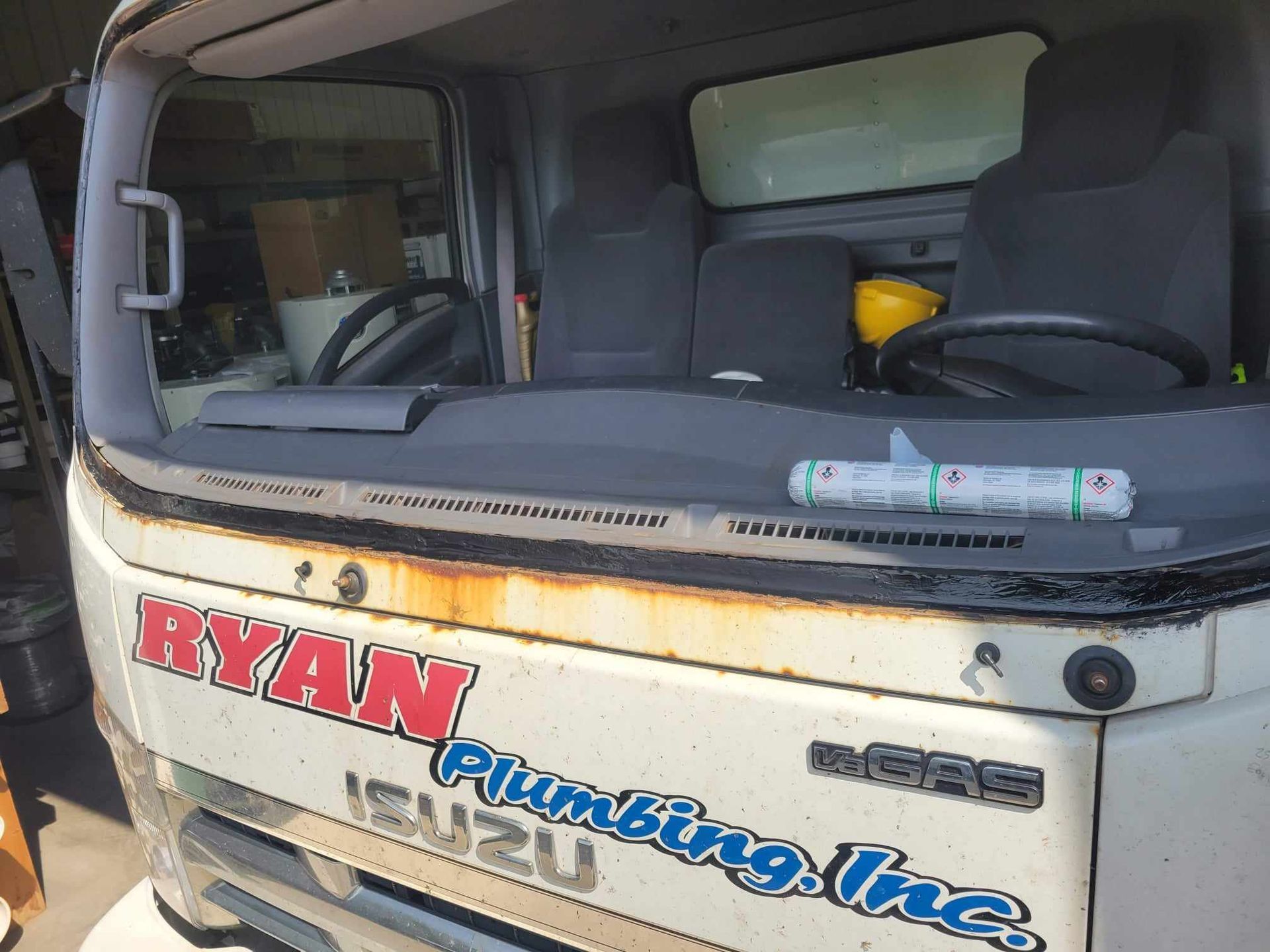 A white ryan plumbing truck is parked in a garage.