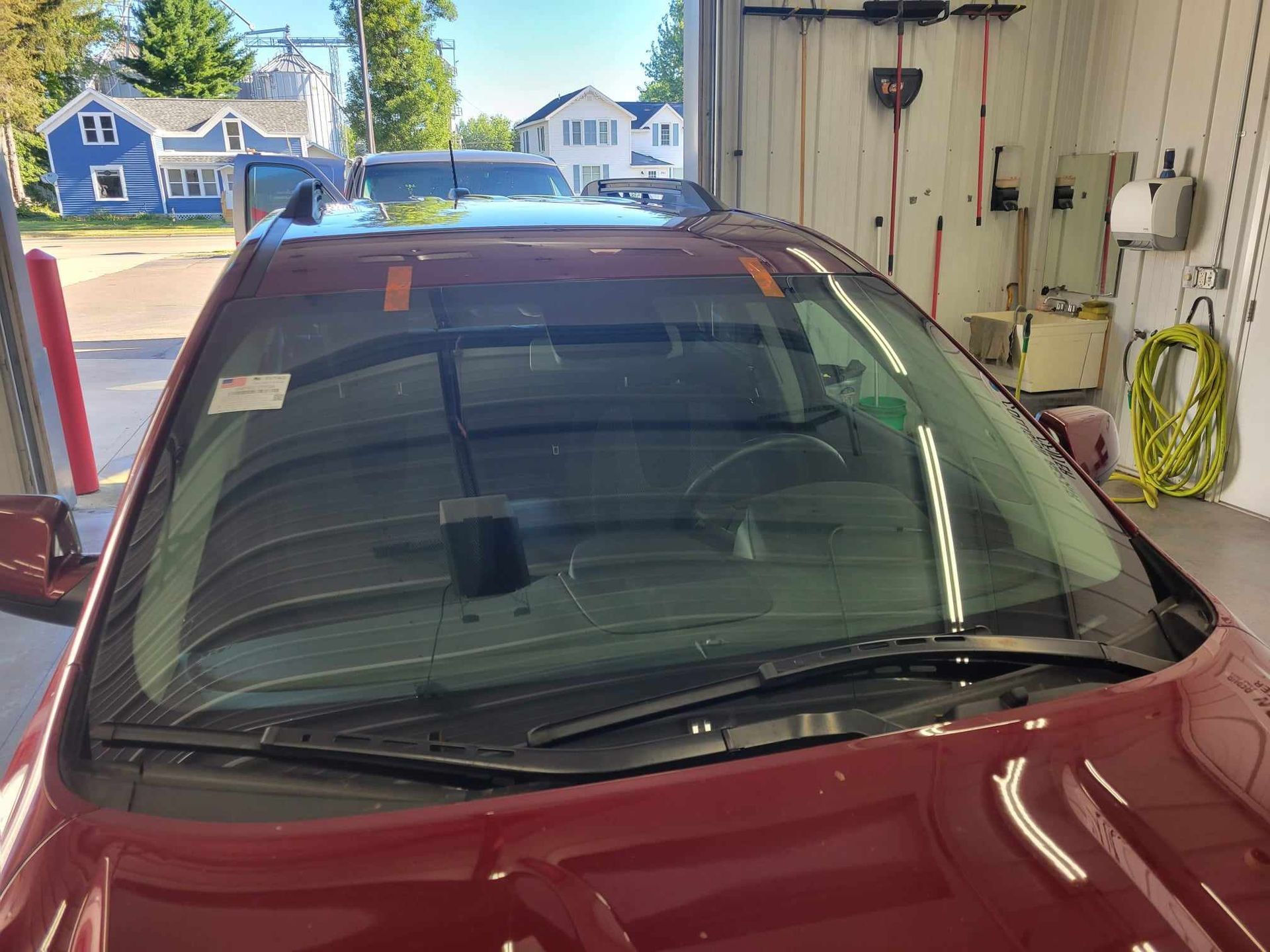 A red car with a new windshield is parked in a garage.