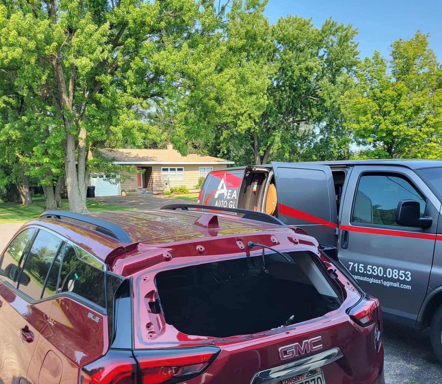 A red suv with a broken windshield is parked next to a van.