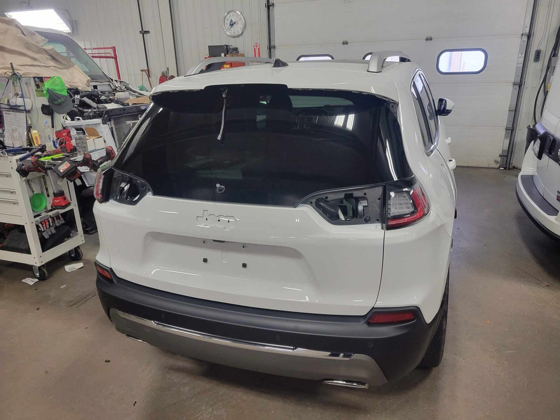 A white jeep cherokee is parked in a garage.