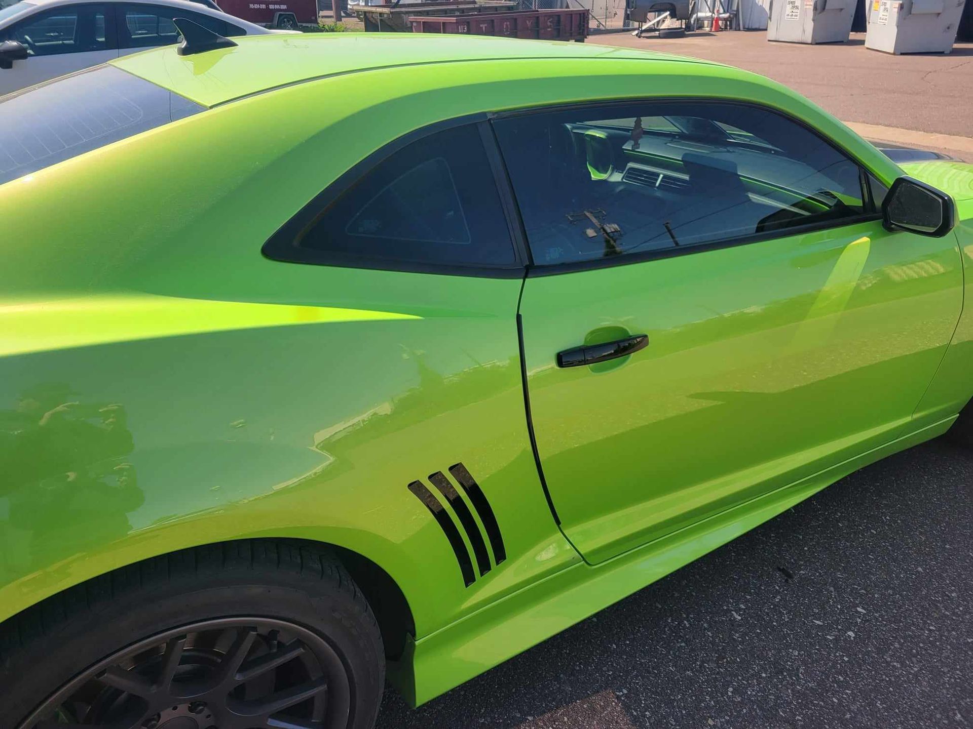A green car is parked on the side of the road.