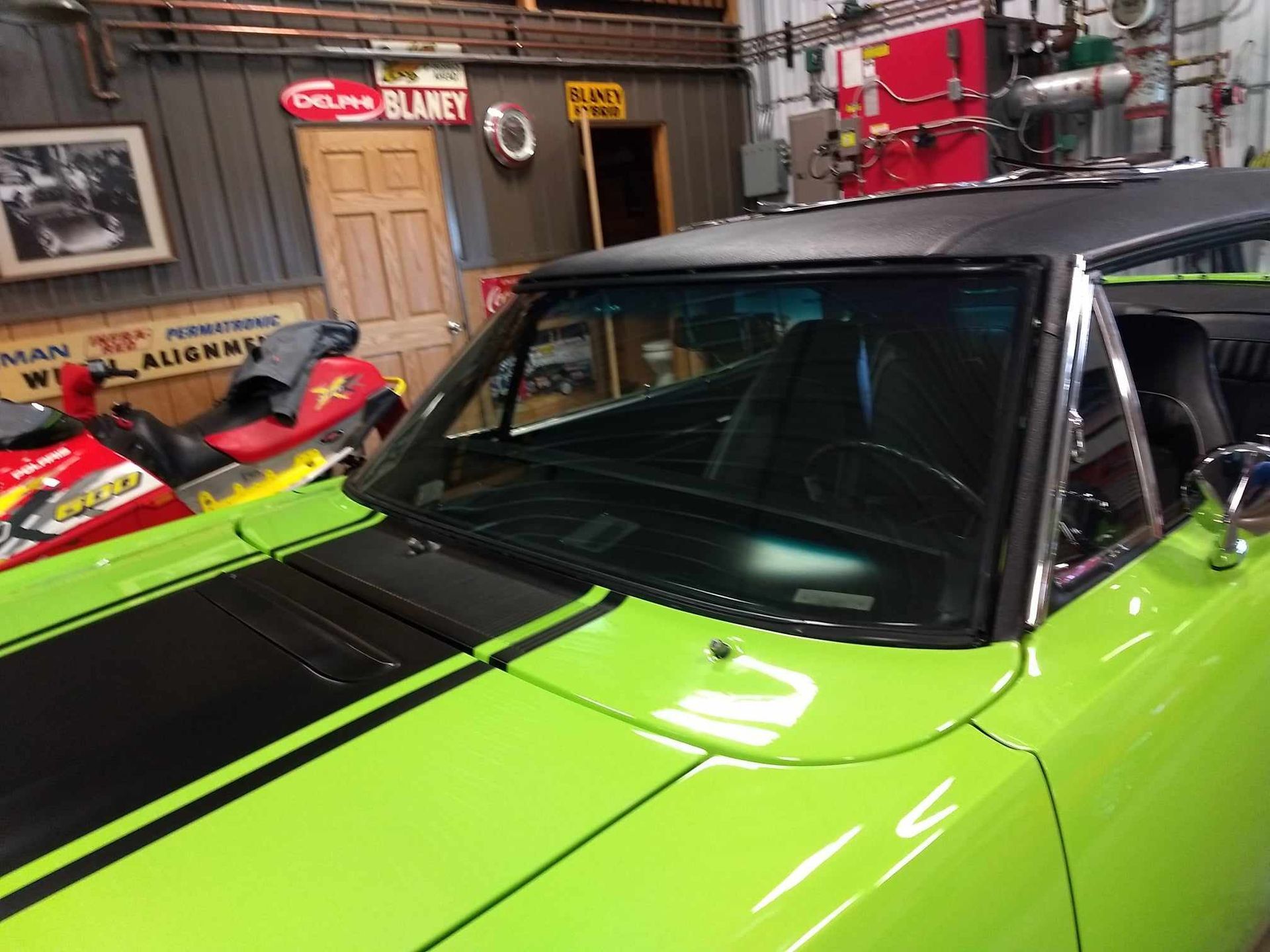 A green car with black stripes is parked in a garage.