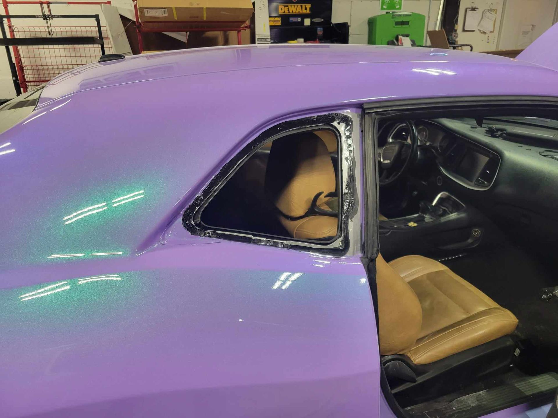 A purple car with a broken window in a garage.