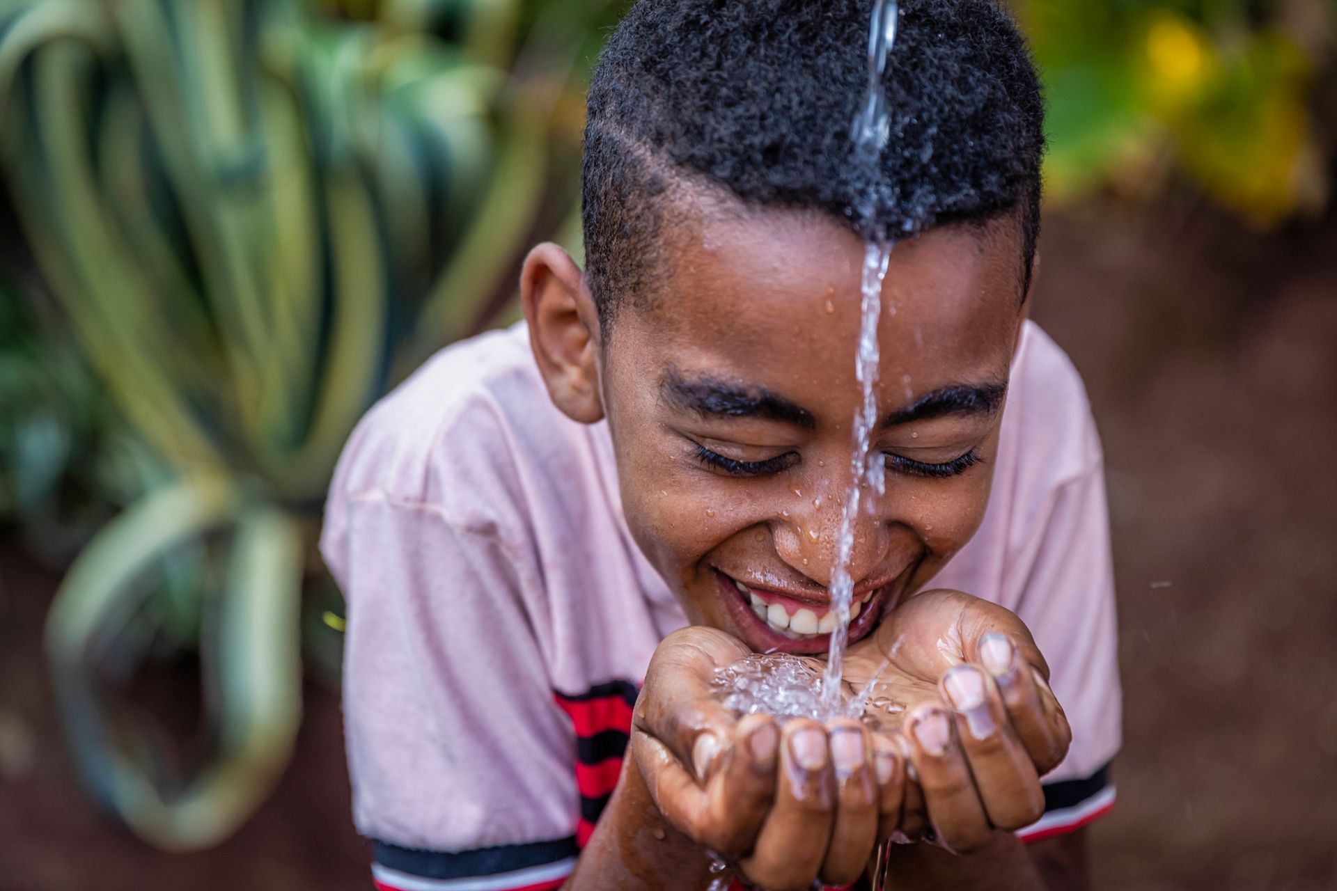 A young boy drinking water directly from a faucet, symbolizing clean, reliable water service provide