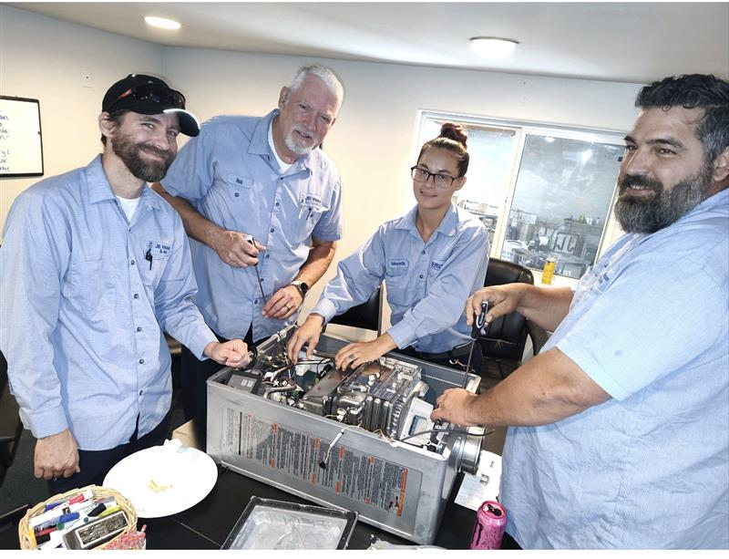 A team of four professionals working together on a machine, demonstrating the commitment to quality 