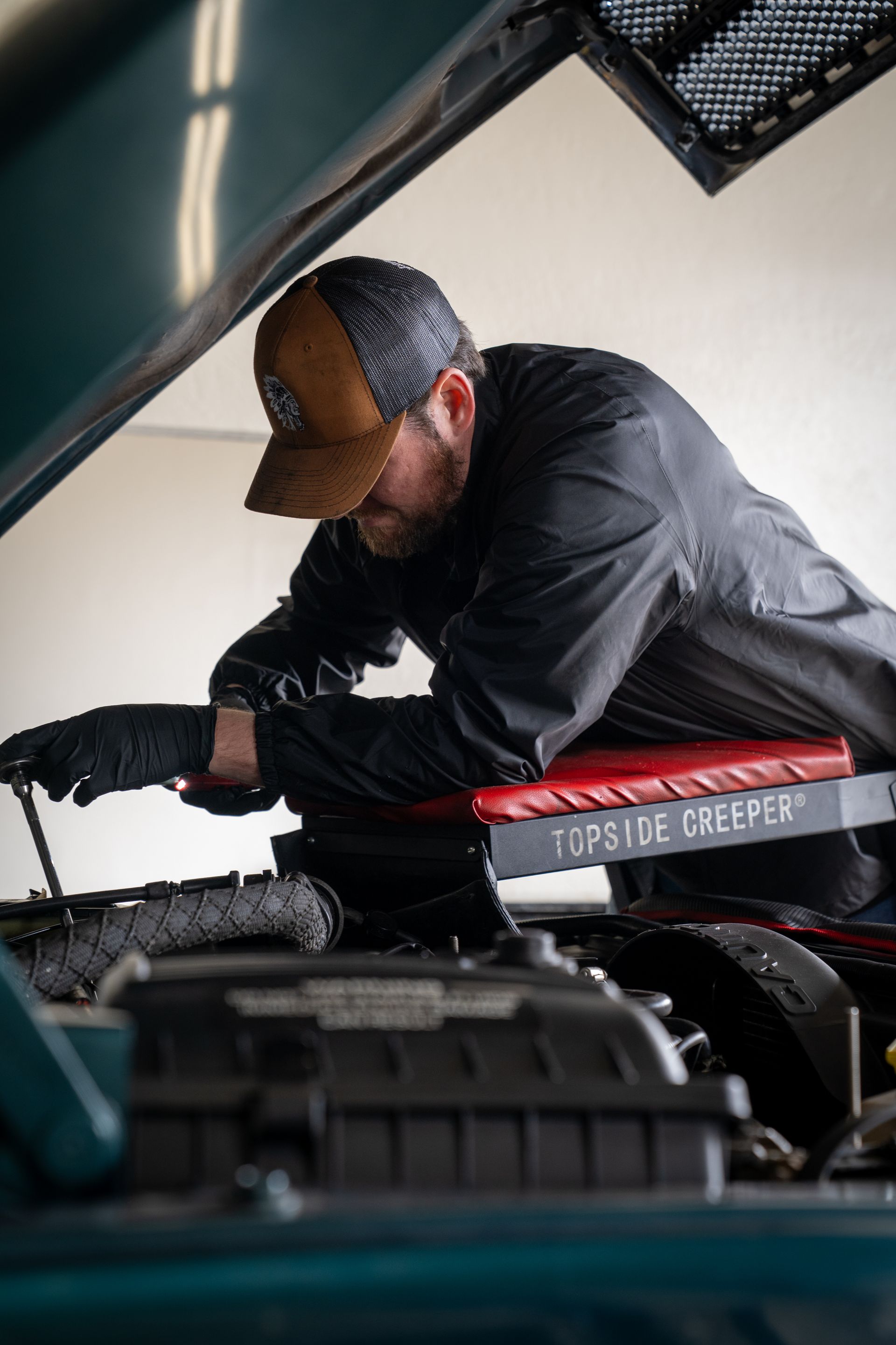A man is working under the hood of a car.