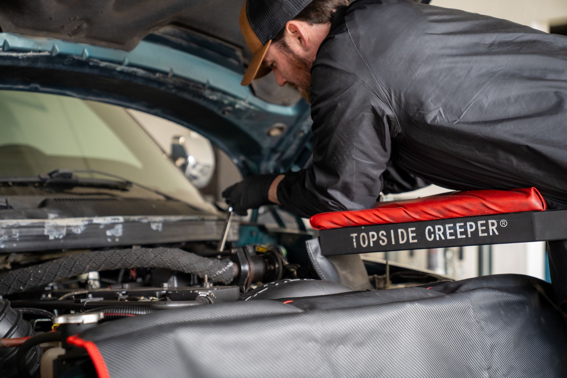 A man is working under the hood of a car.