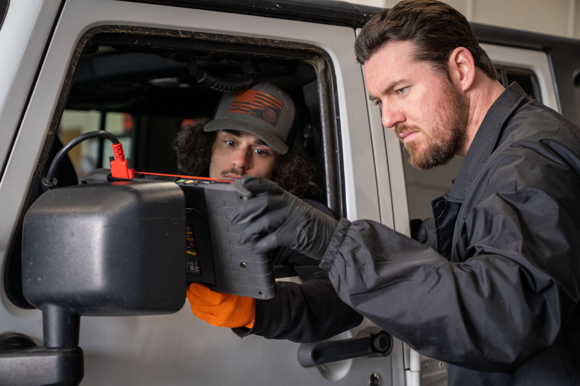 Two men are working on a car in a garage.