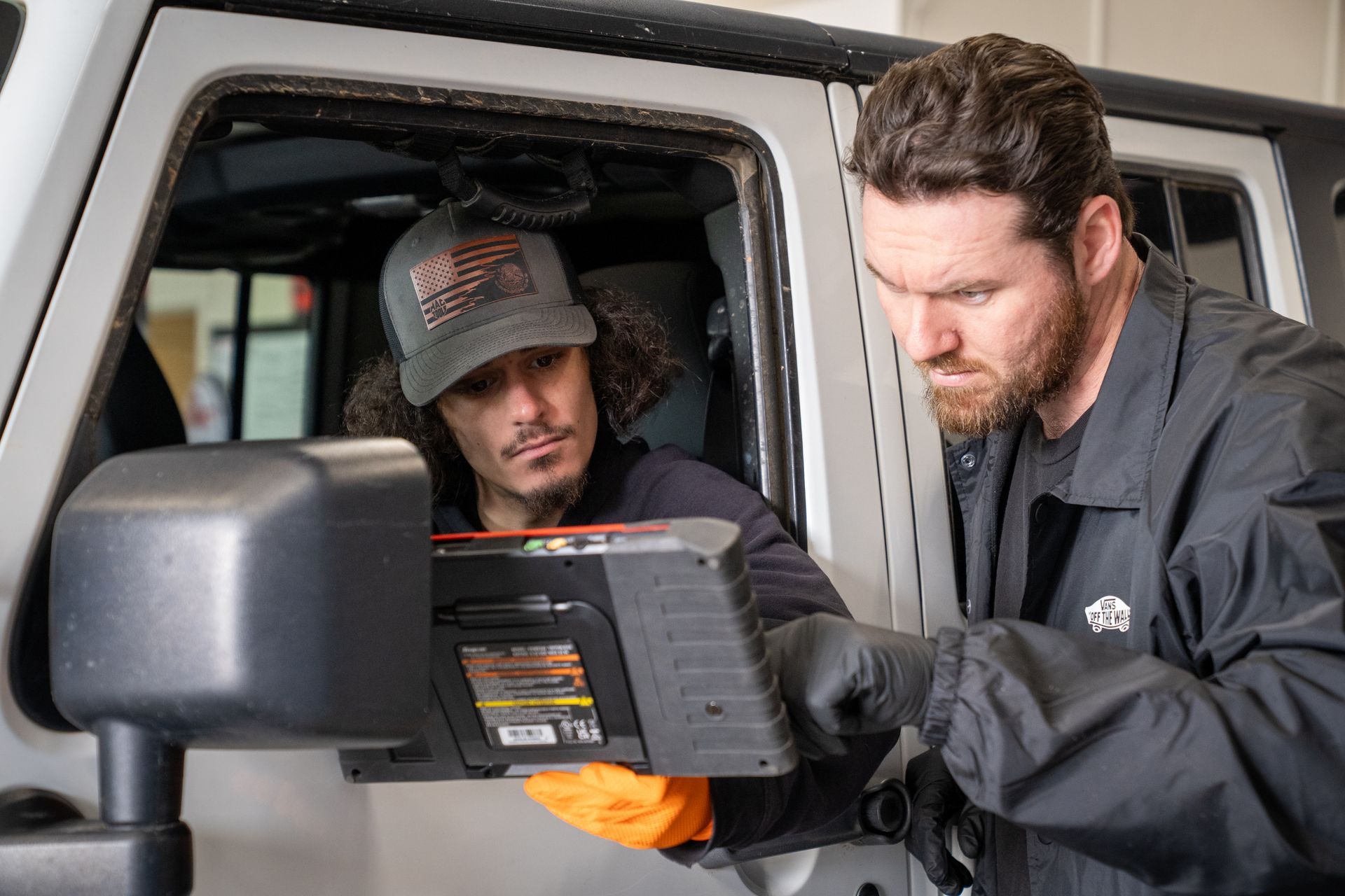 Two men are working on a jeep in a garage.