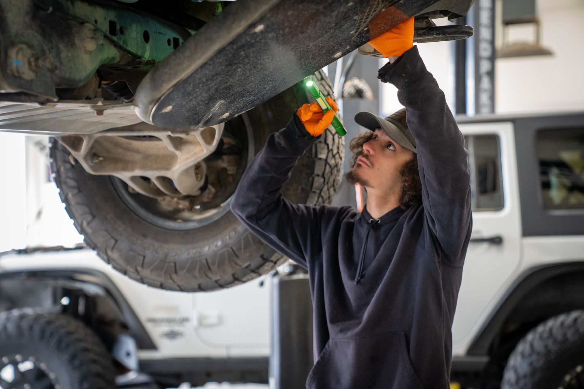 A man is working on the underside of a car in a garage.