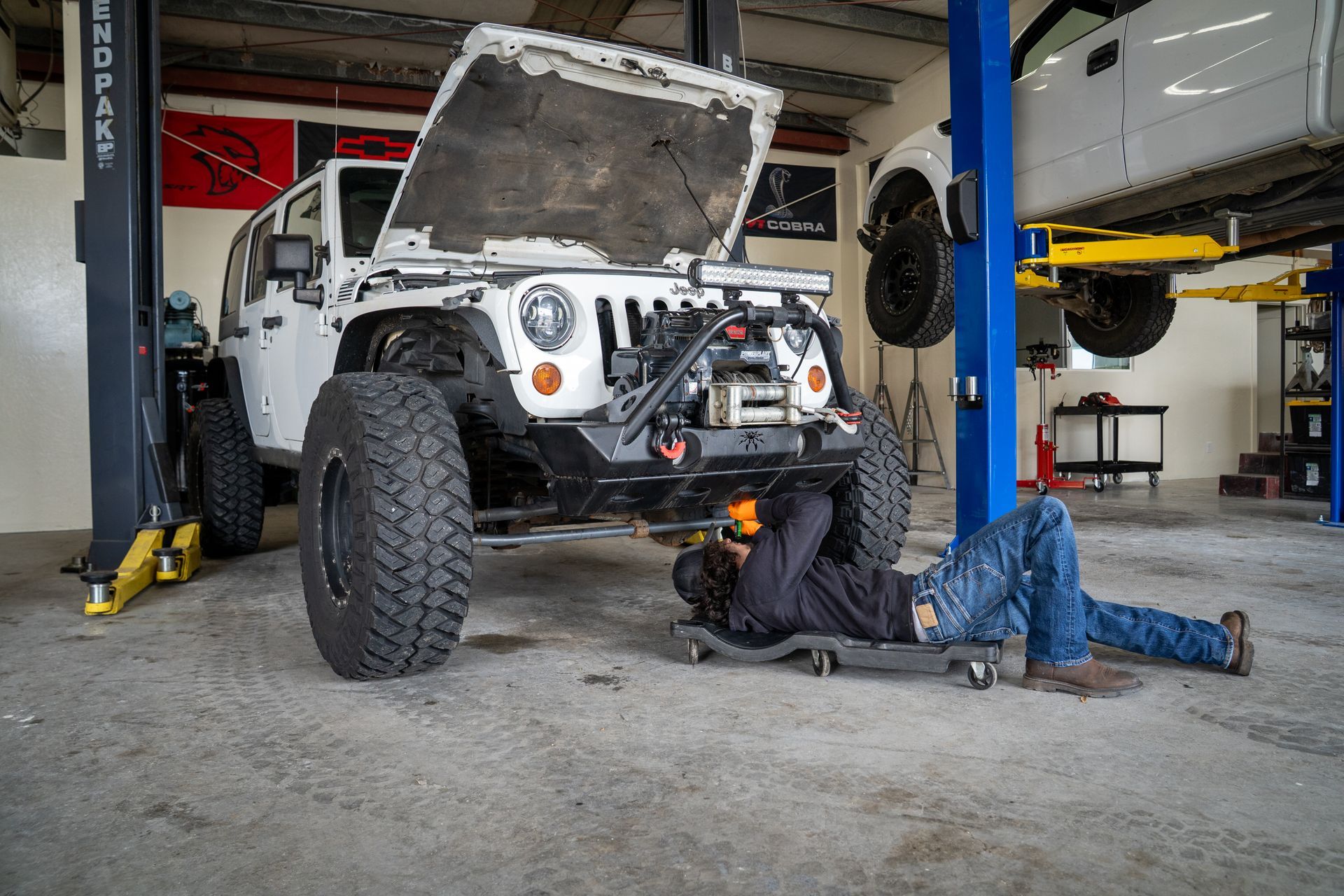 A man is working on a jeep in a garage.