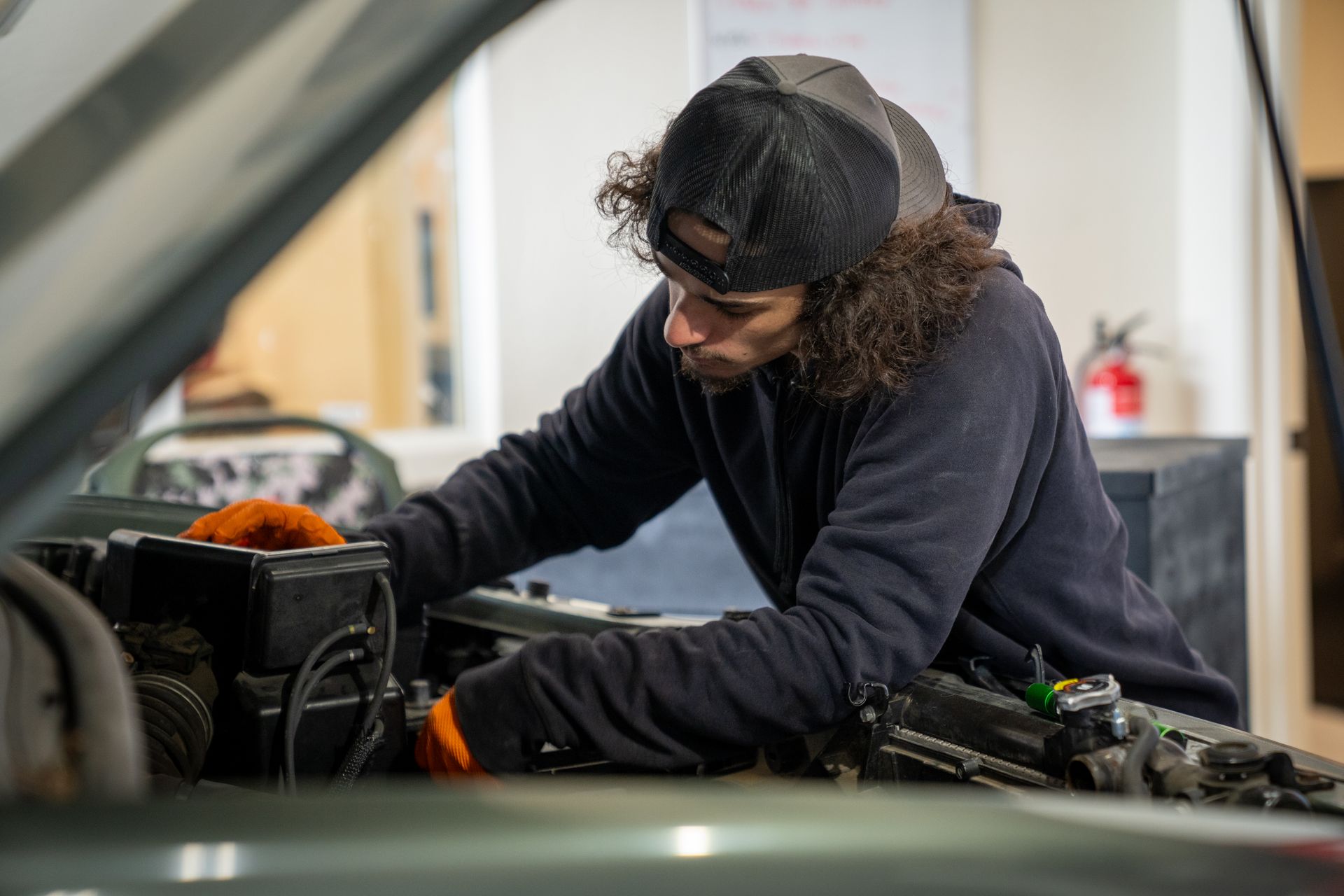 A man is working on the engine of a car in a garage.