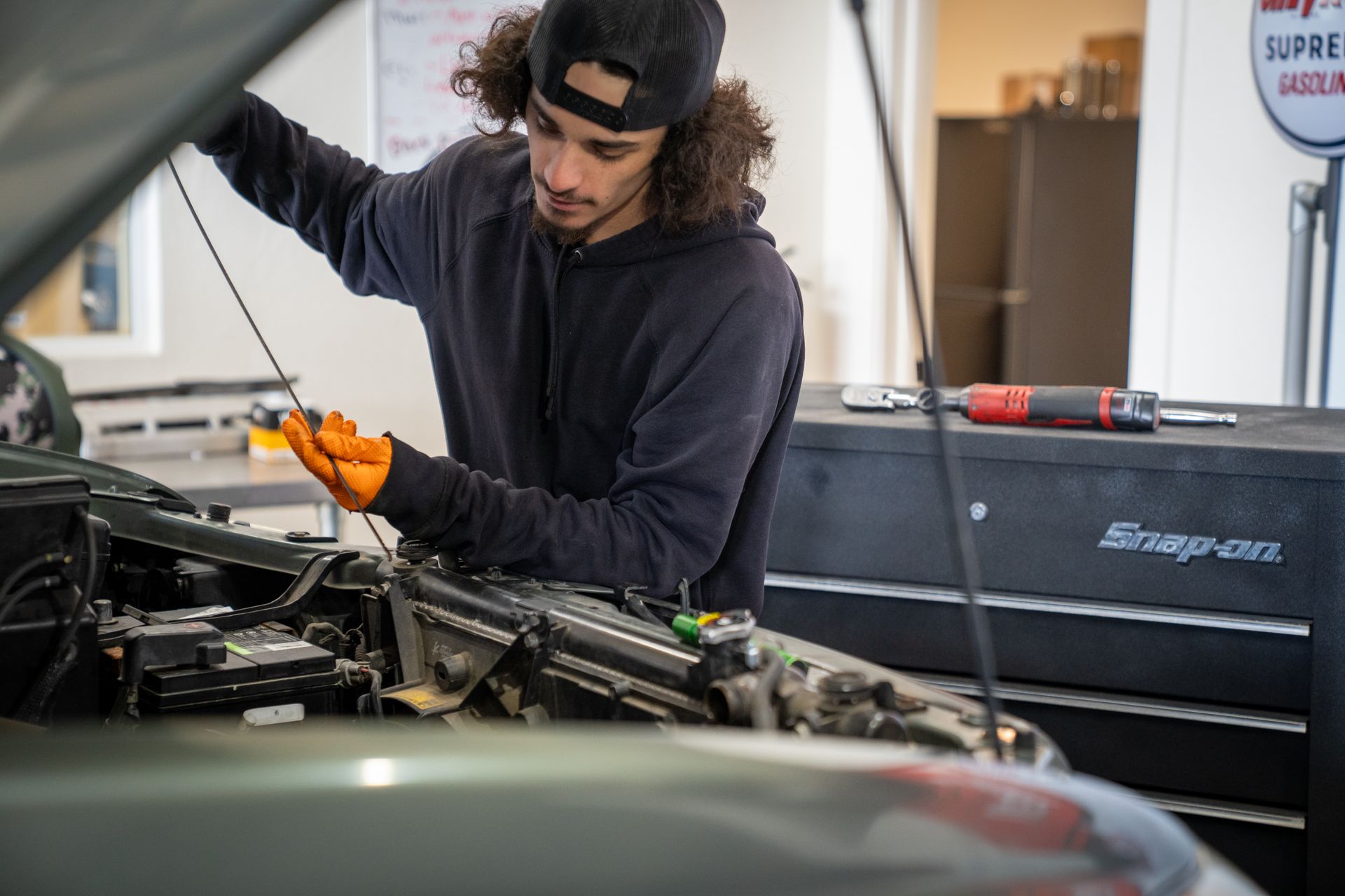A man is working on the engine of a car in a garage.