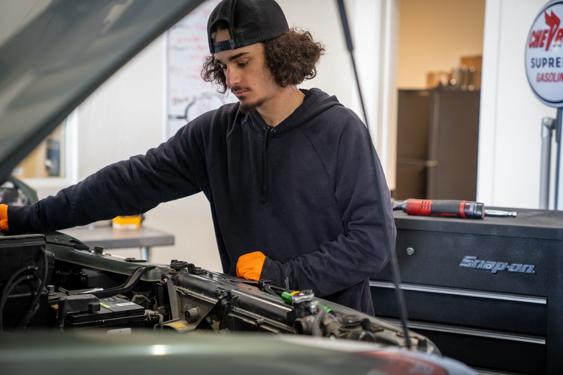 A man is working on the engine of a car in a garage.