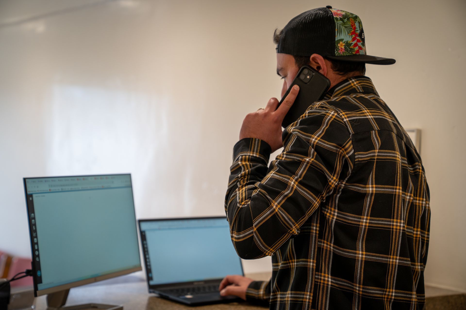 A man is sitting at a desk talking on a cell phone.