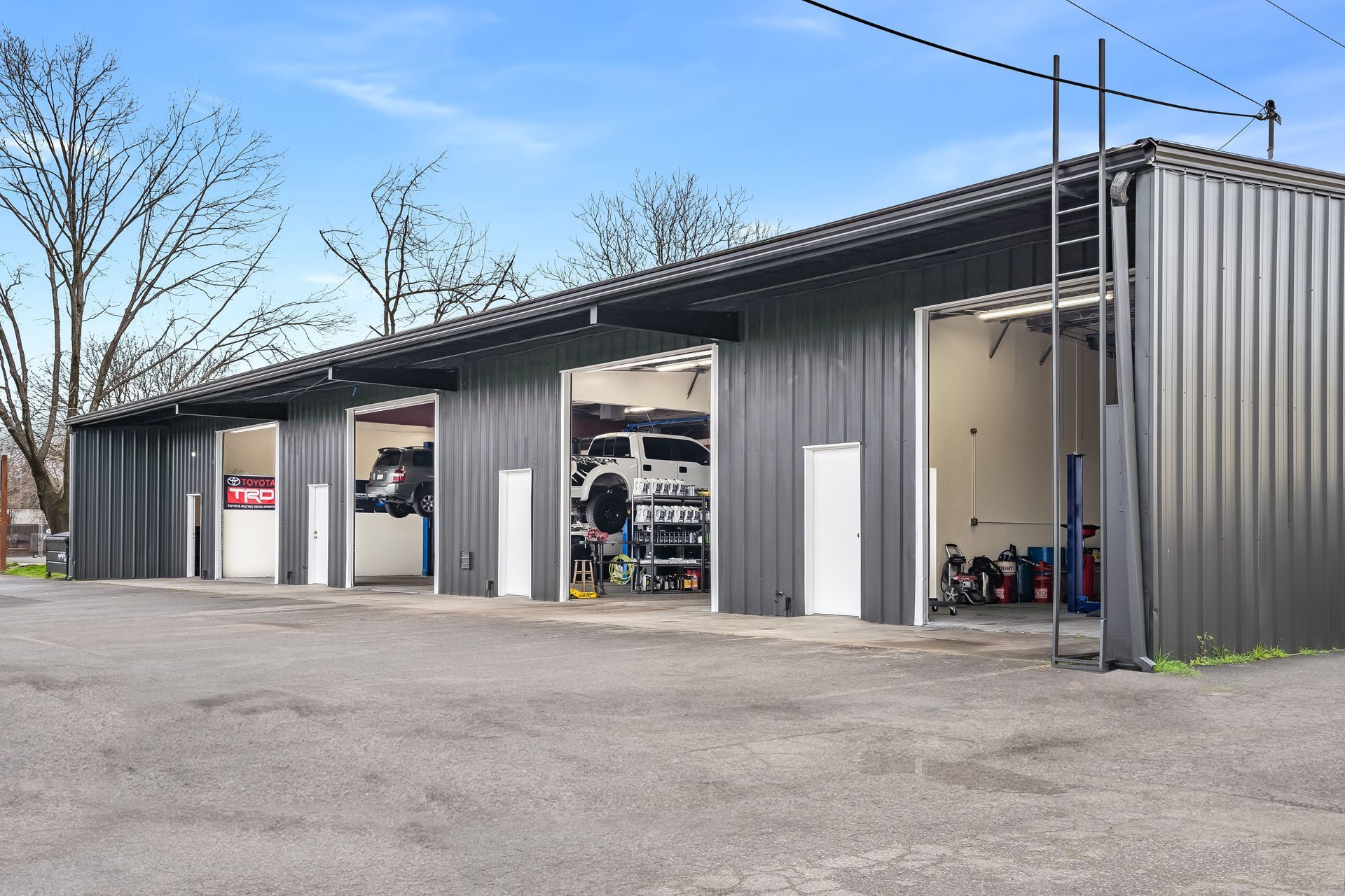 A row of garages with cars parked inside of them