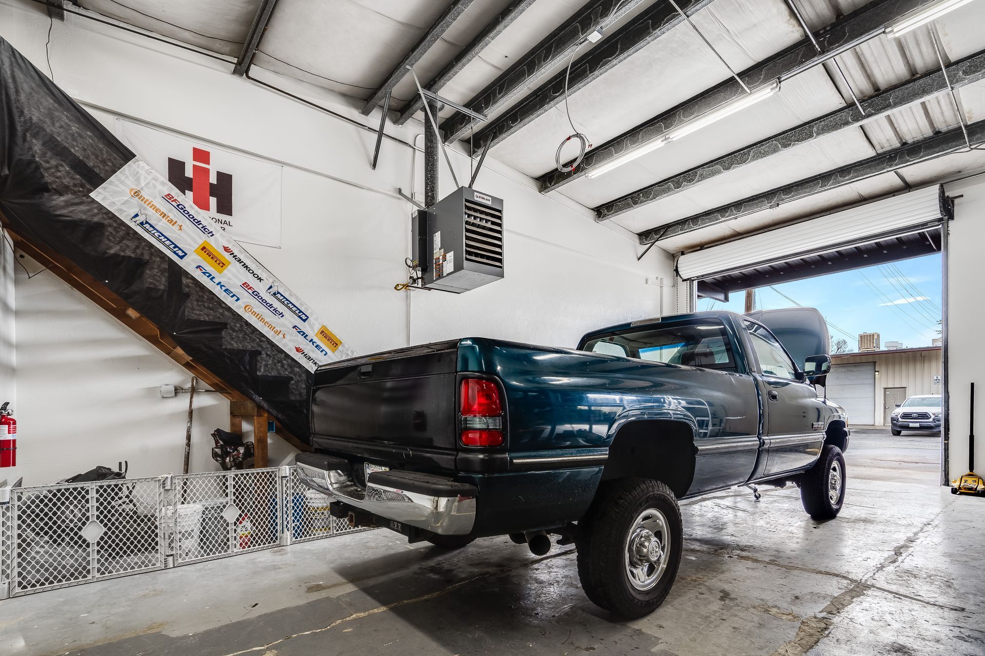 A truck is parked in a garage with the door open.