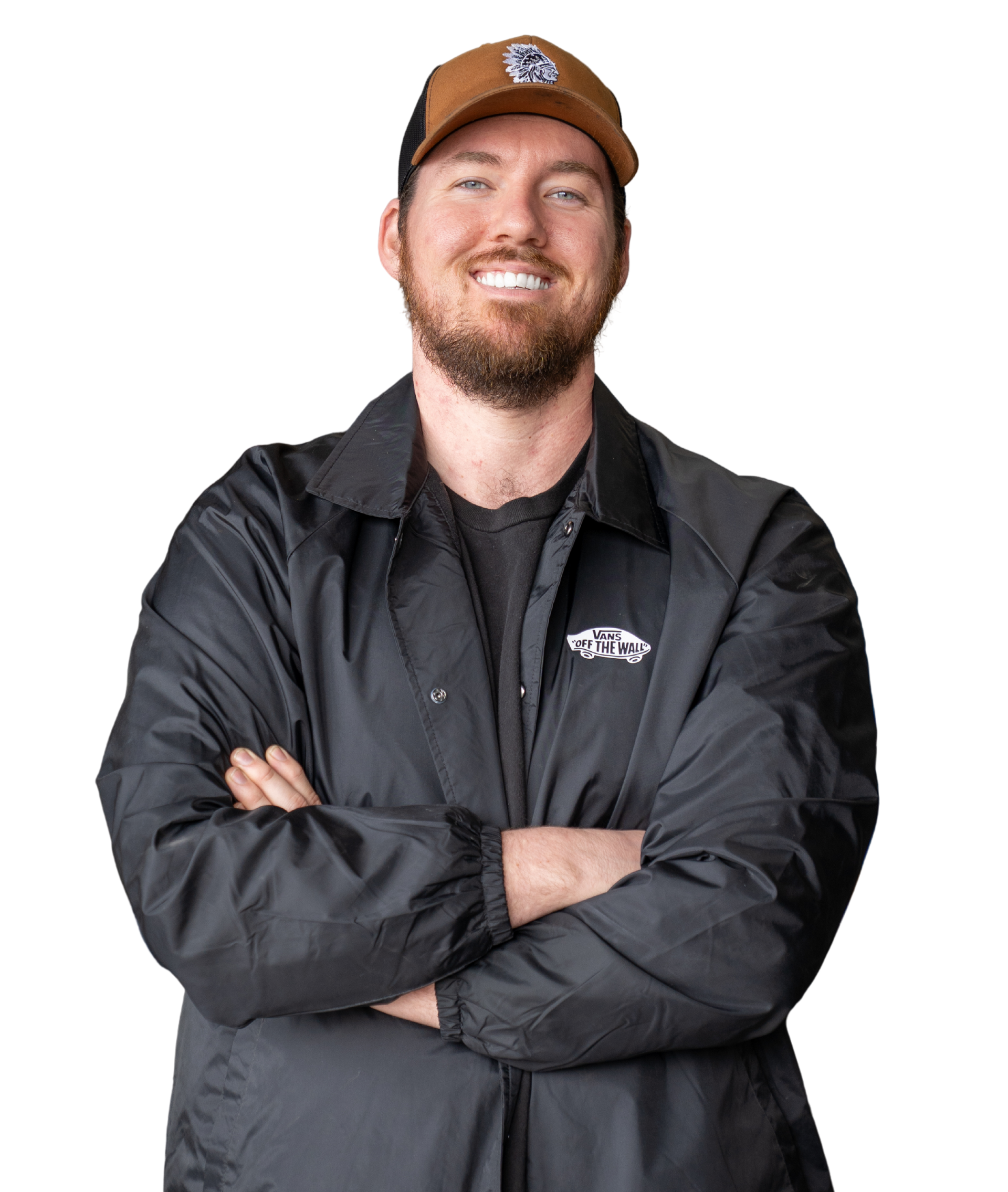 A man in a blue jumpsuit is holding a wrench and smiling. A man with a beard is wearing a hat and a black jacket.