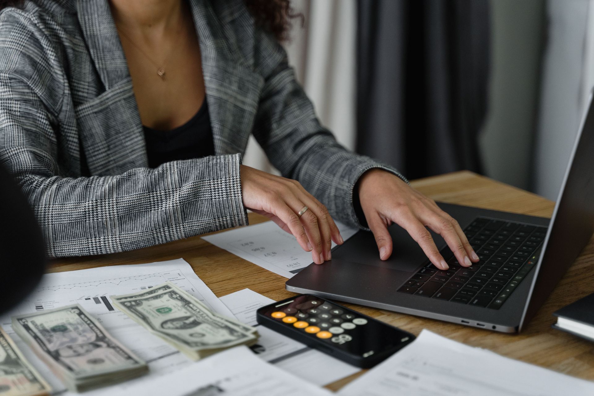 Person using a laptop with bills and a calculator on a desk