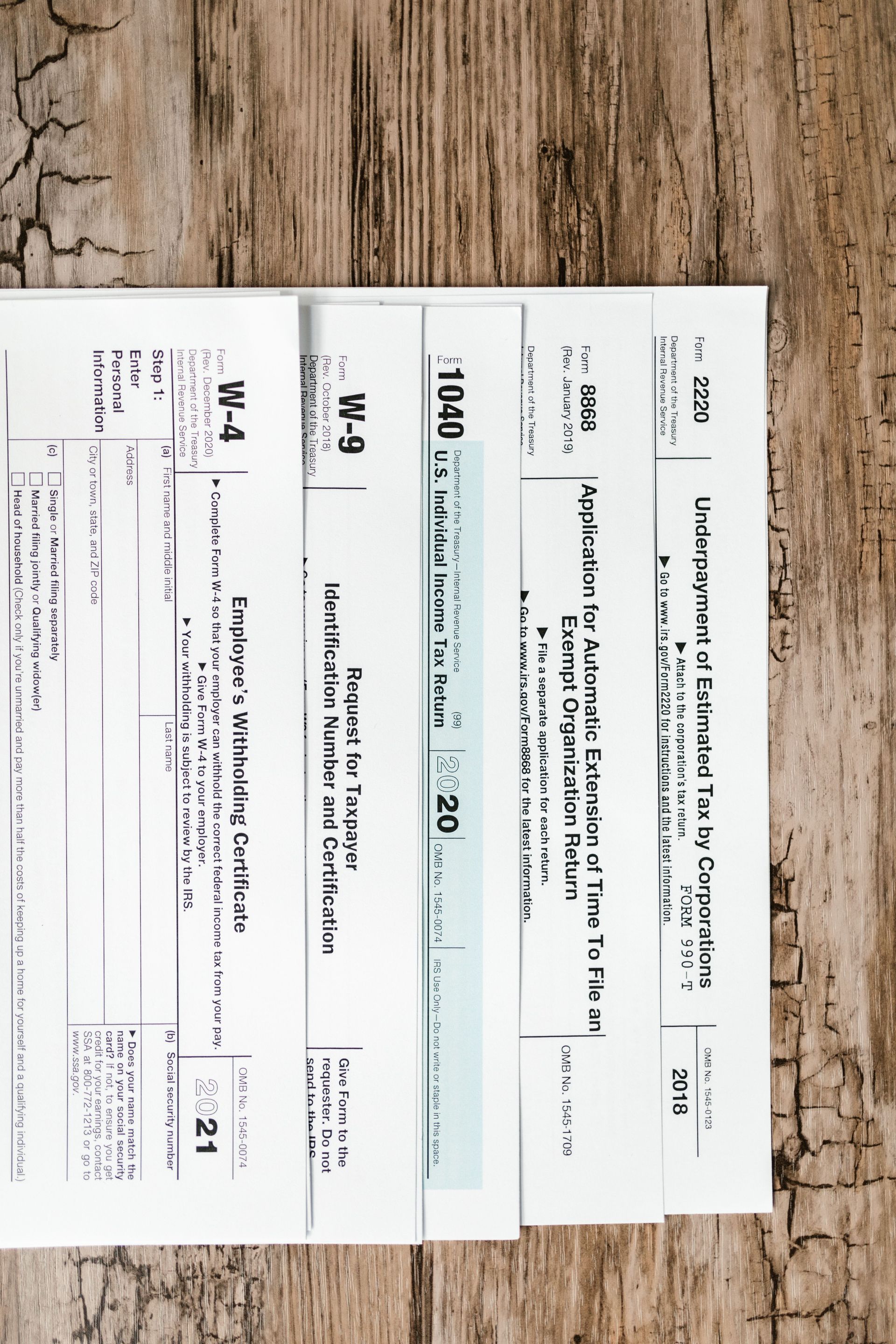 Stack of white papers with handwritten notes on a wood surface.