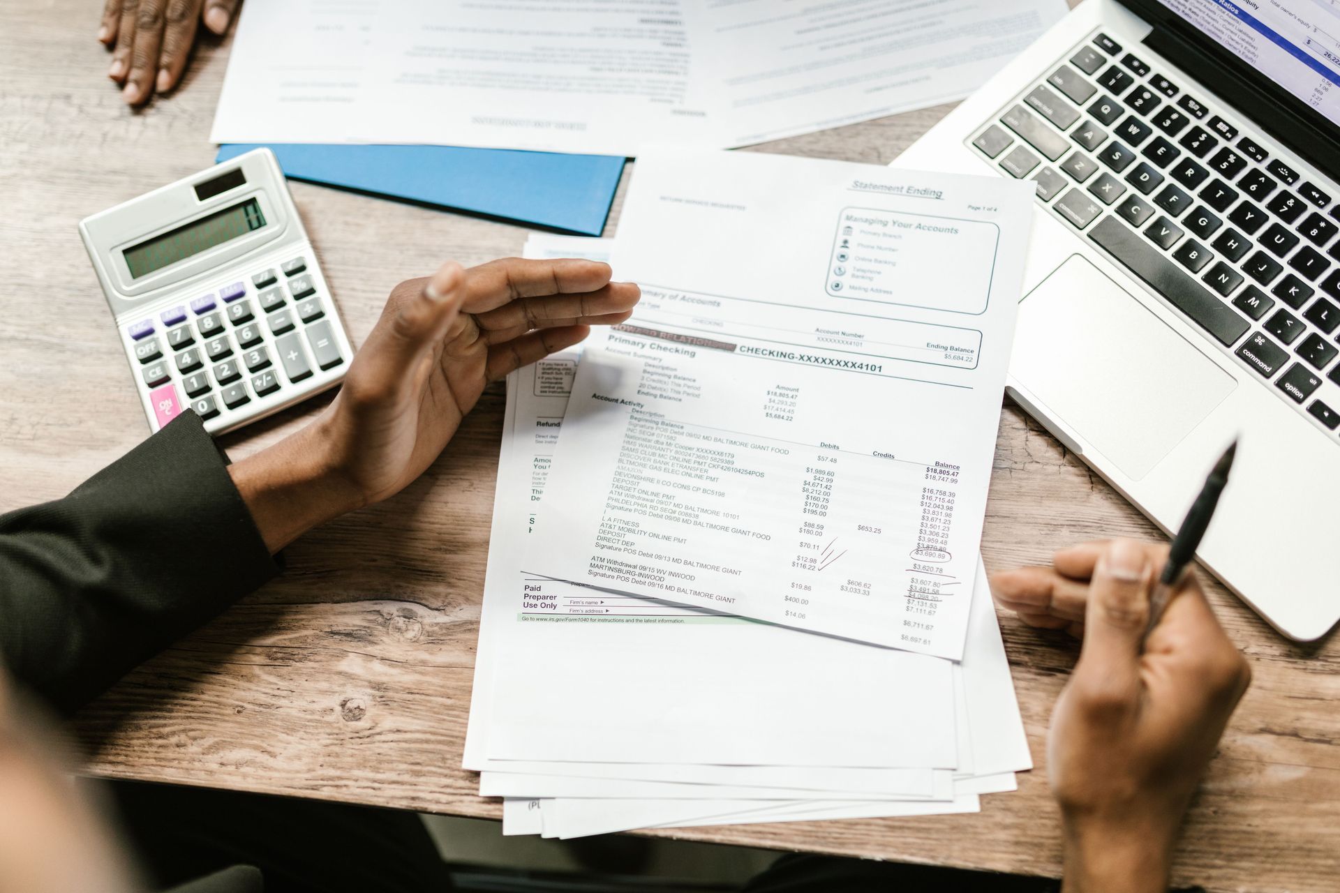 Hands reviewing invoices and receipts with calculator and laptop on a desk