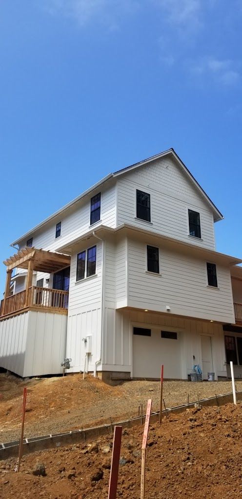 A large white house is sitting on top of a dirt hill.