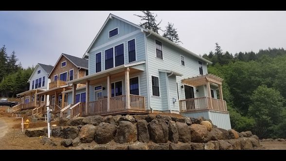 A large house is sitting on top of a rocky hill surrounded by trees.