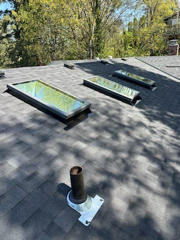 A roof with three skylights and a chimney on it.