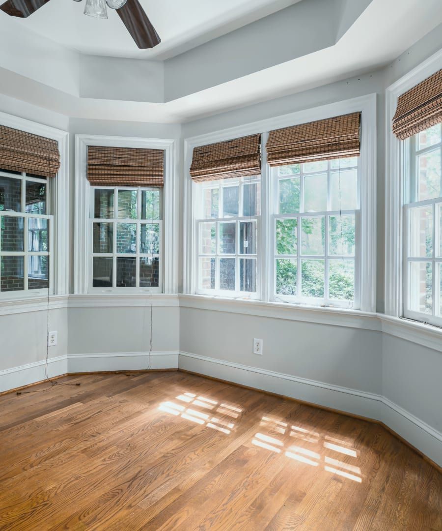 An empty room with a lot of windows and a ceiling fan.