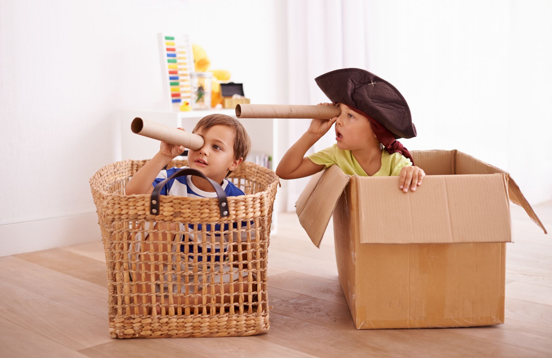 Two children pretending to be pirates using cardboard boxes as their ships