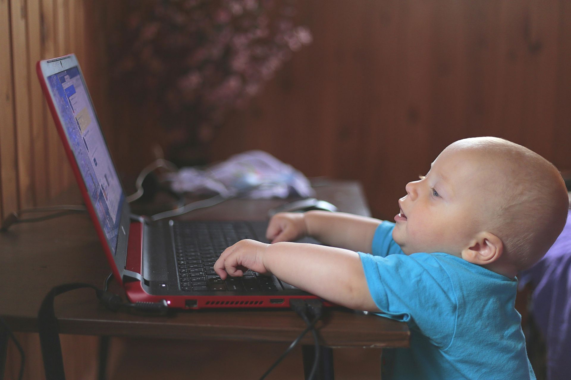 A baby is sitting at a table using a laptop computer.