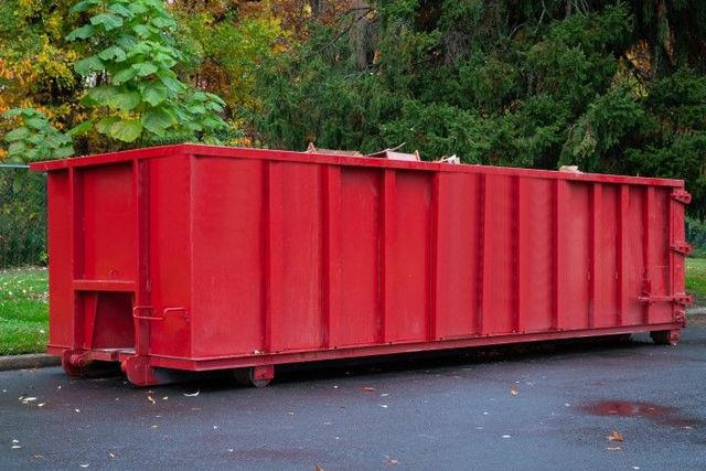 A large red dumpster is parked on the side of the road.