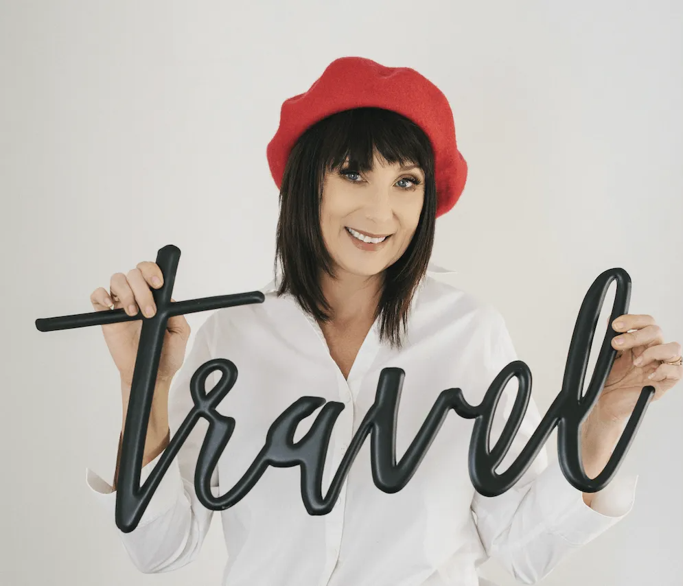 A woman in a red beret is holding a sign that says travel