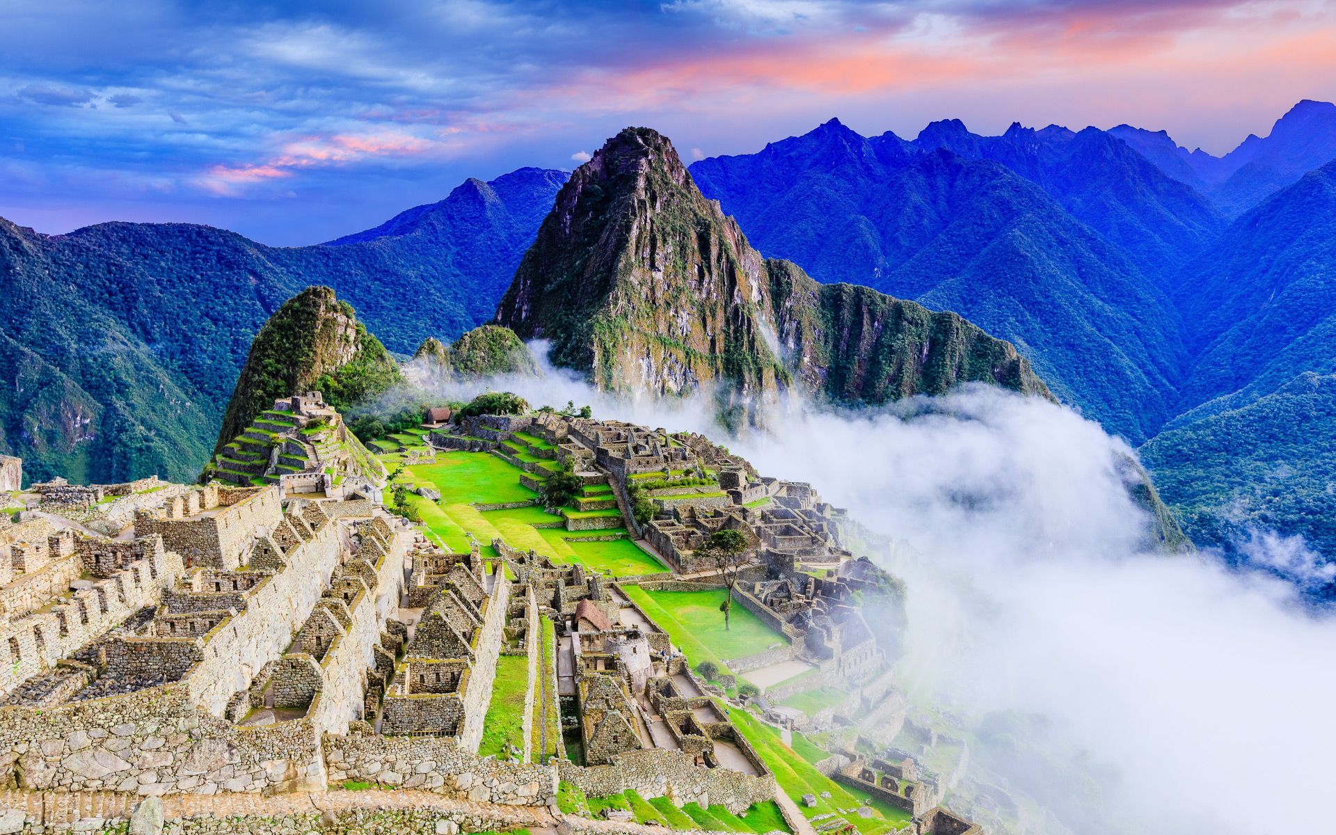 The ruins of machu picchu are surrounded by mountains and clouds.