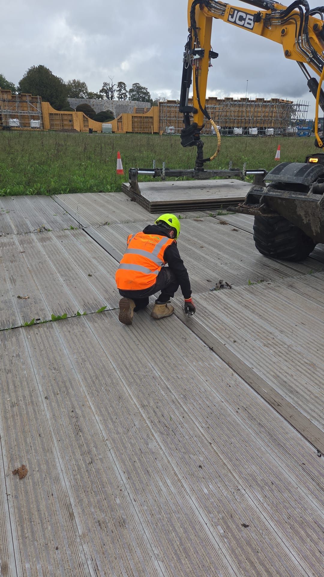 Red brick building with dark roof and dormer windows, tree branches in the sky.