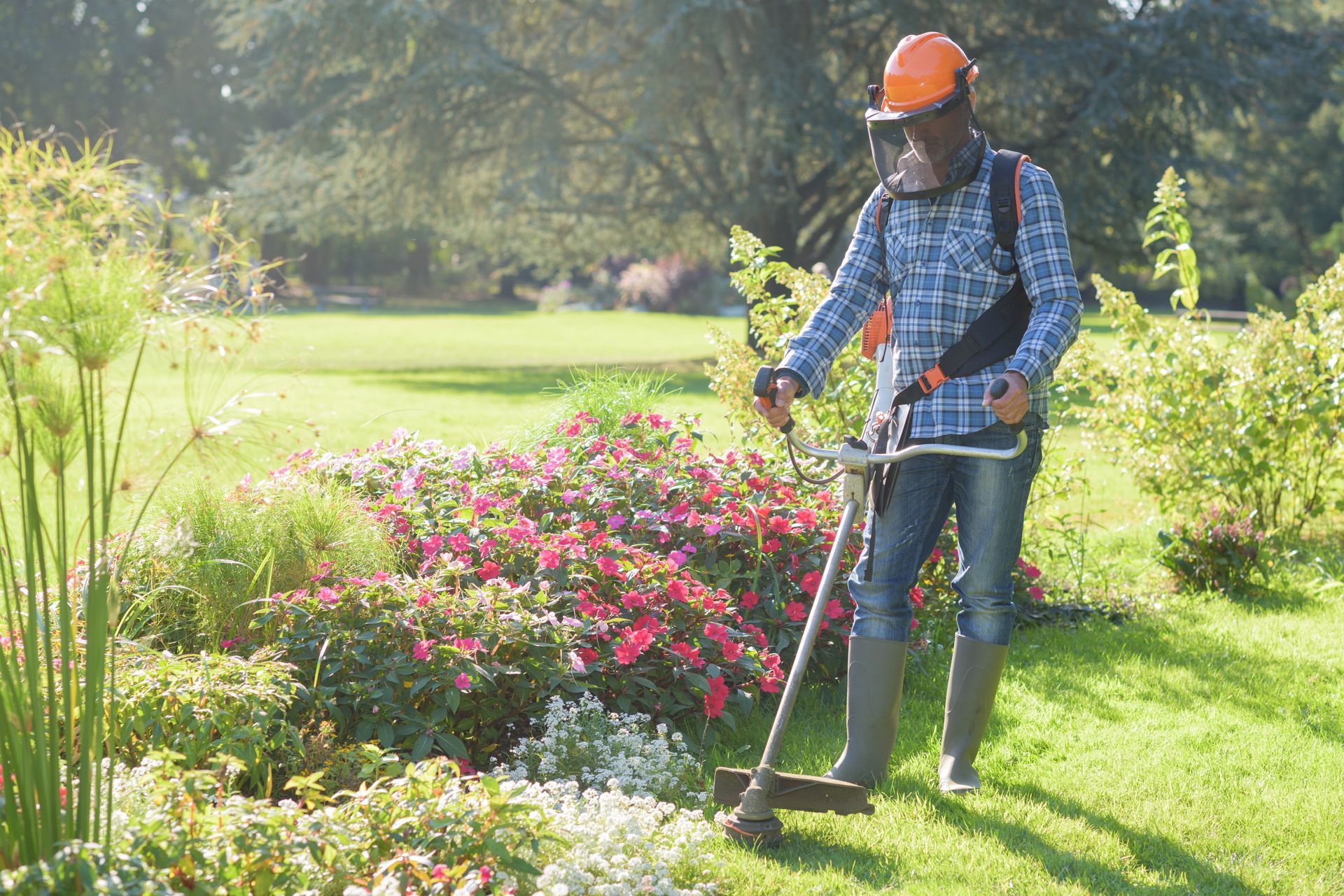 a man wearing a hard hat is using a lawn mower in a garden