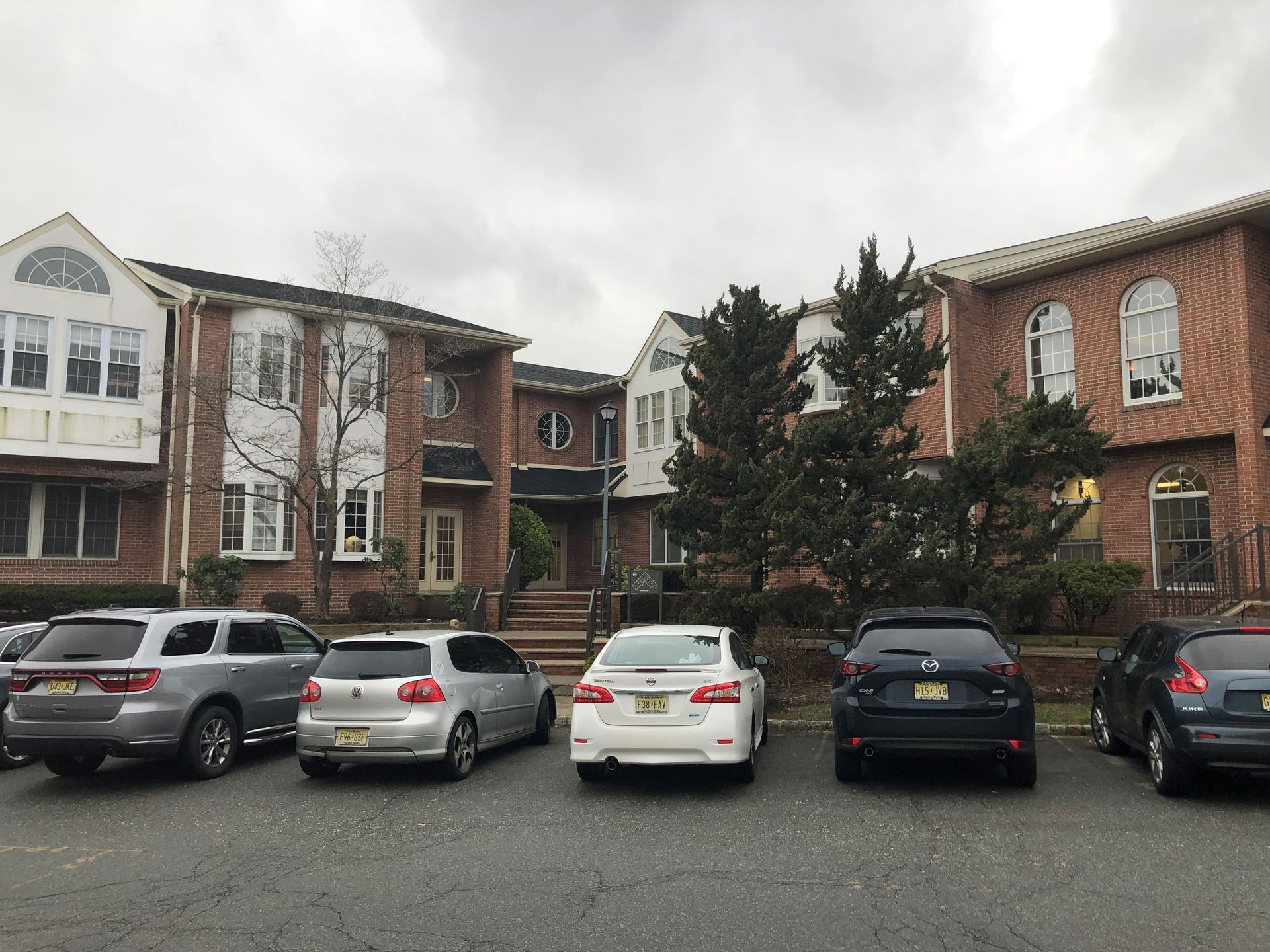 A row of cars are parked in front of a brick building.