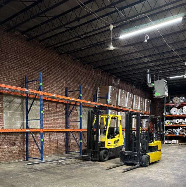 Two forklifts are parked in a large warehouse