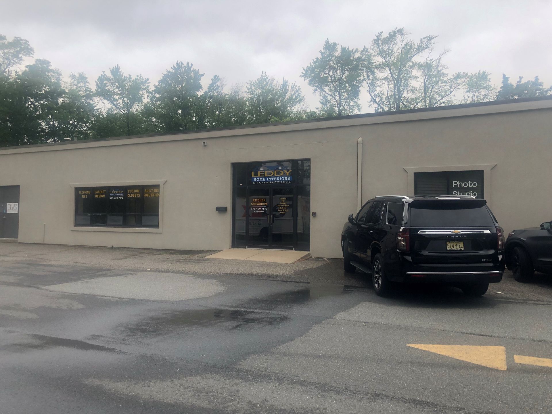 A black suv is parked in front of a building.