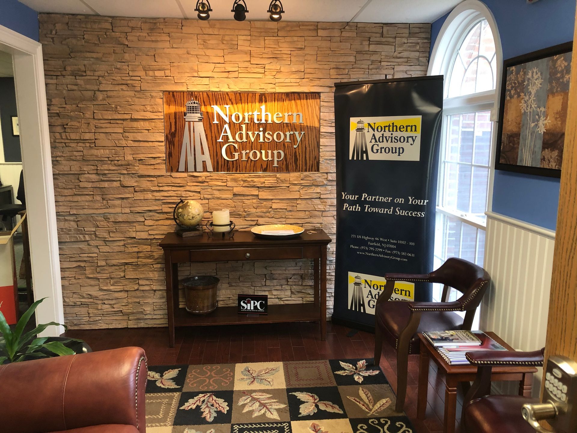 Office waiting area with stone accent wall, Northern Advisory Group sign, and seating.