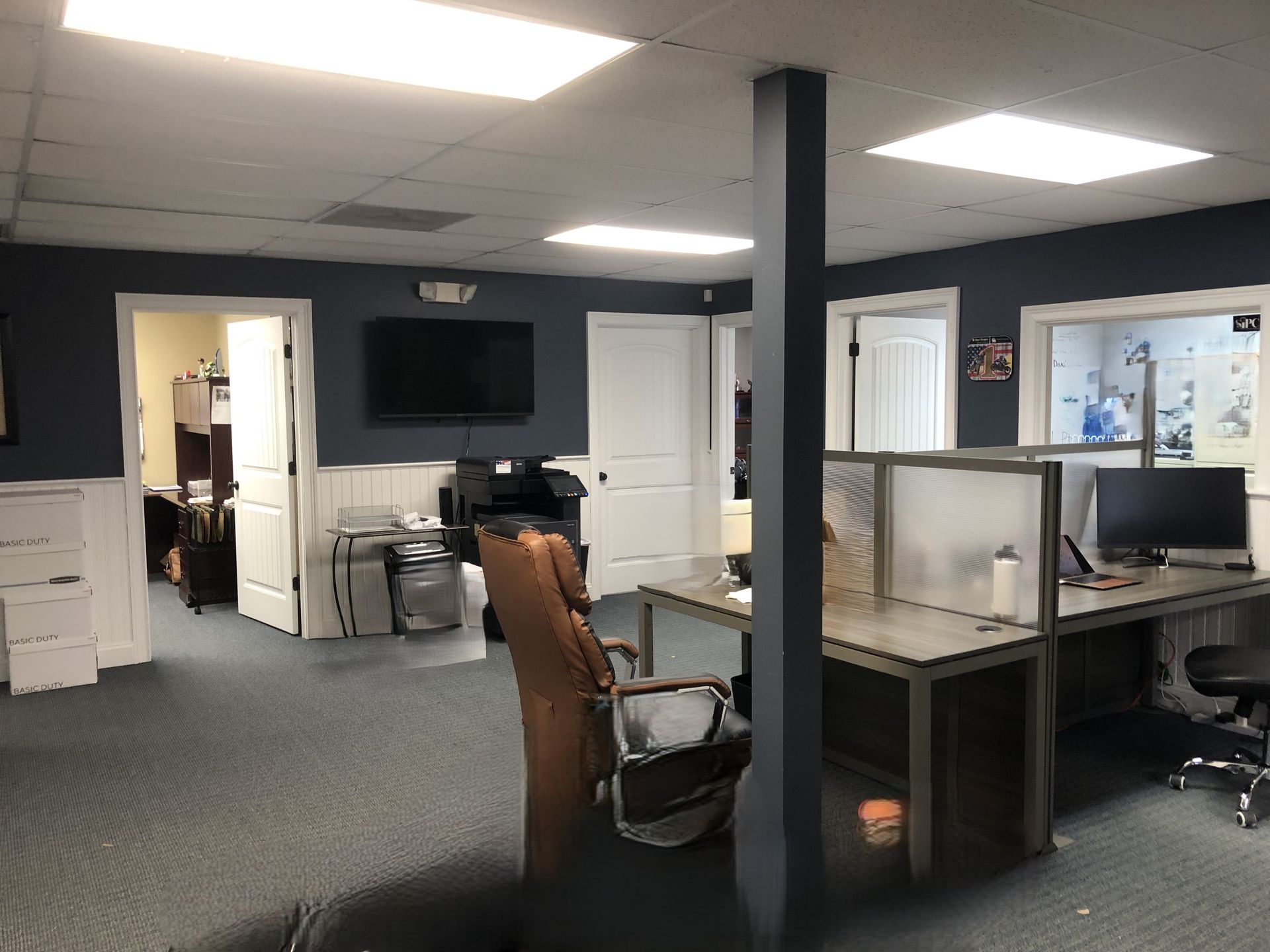 Office space with desks, chairs, computer, TV, and blue walls.