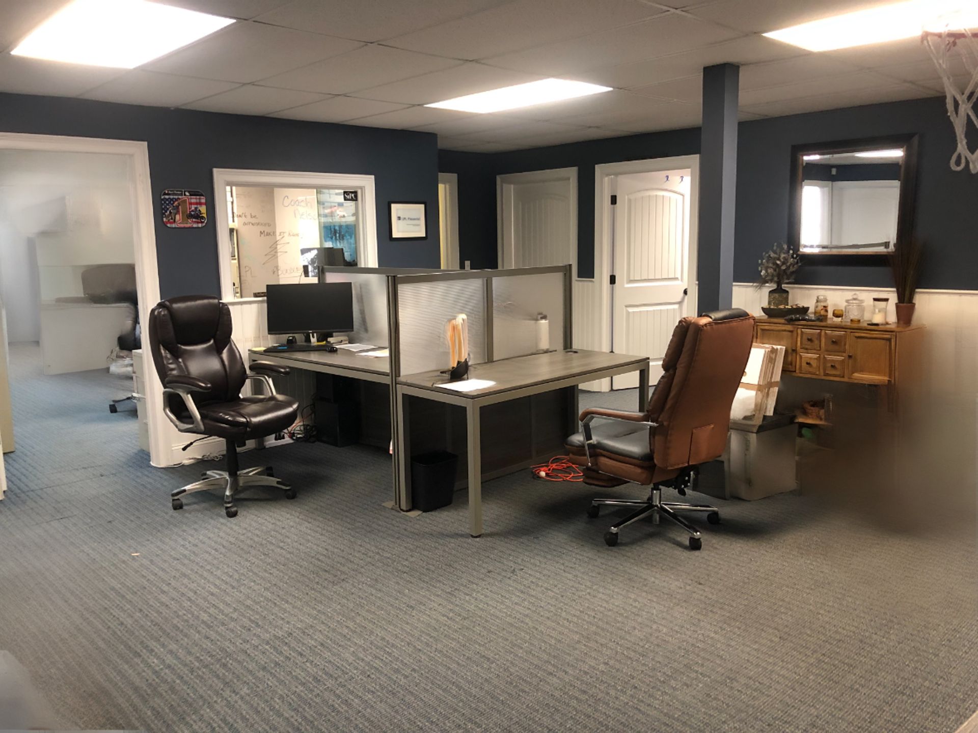Office interior with blue walls, gray desks, and several office chairs.