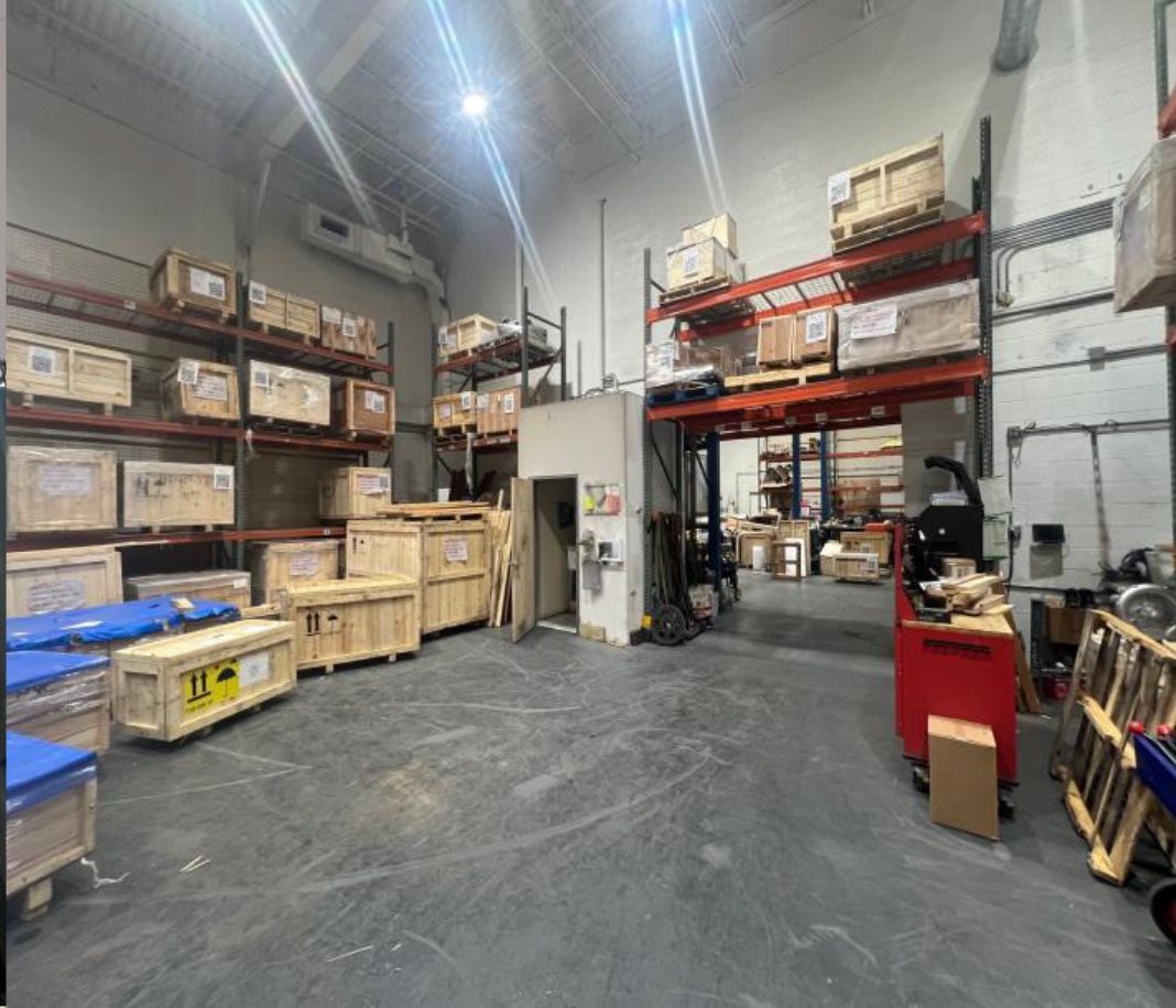 Warehouse interior with shelves of packed wooden crates and boxes, forklift, concrete floor.
