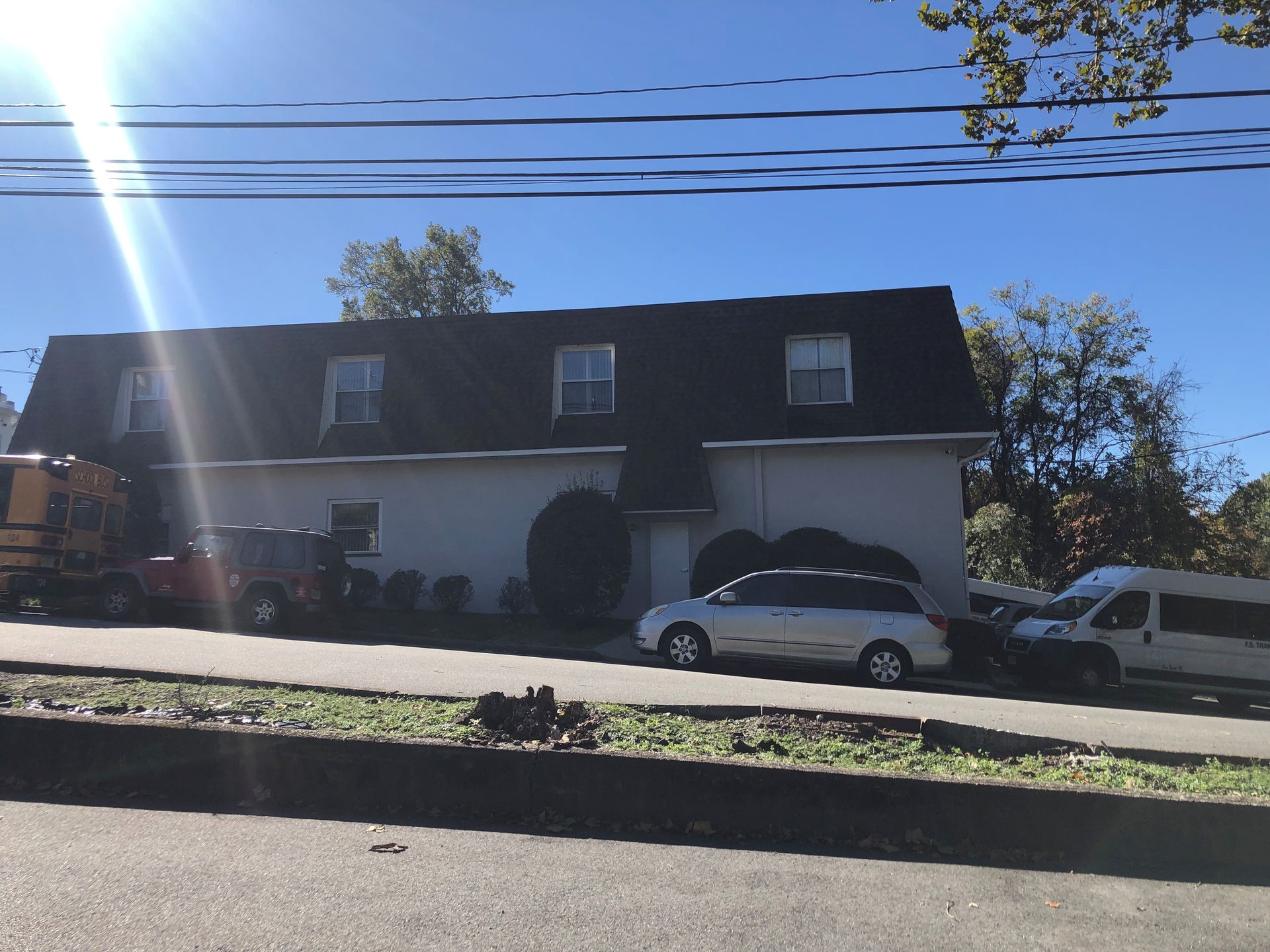 Building with black roof and cars parked in front on a sunny day.