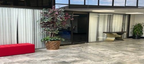 Exterior of a building with a red bench, large plant, and a gold table.